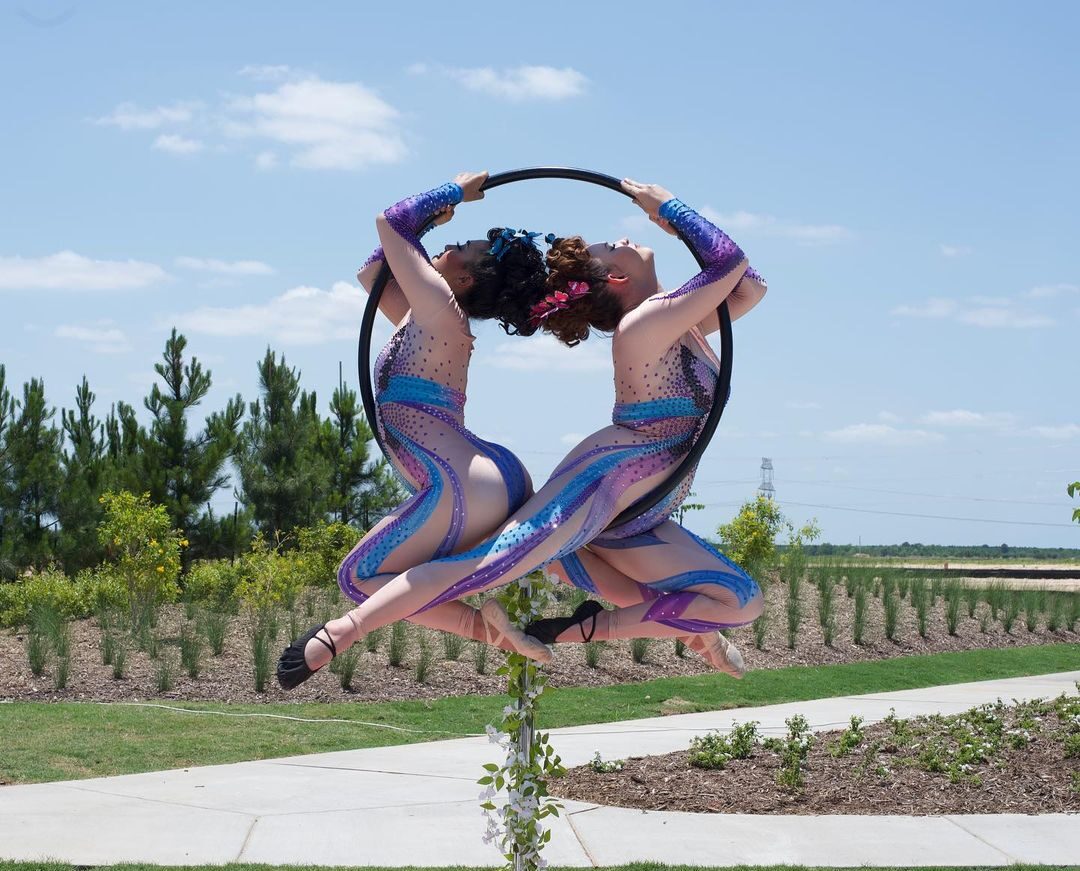 Two aerialists pose inside of a lyra