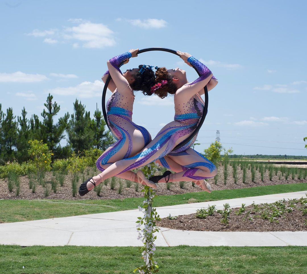 Two performers pose inside of a lyra hoop