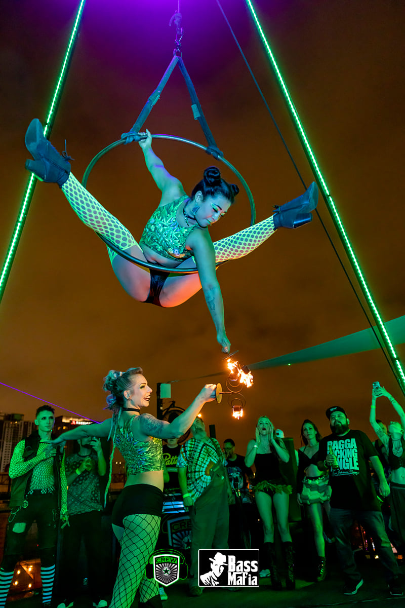 An aerialist wields torches inside of a lyra