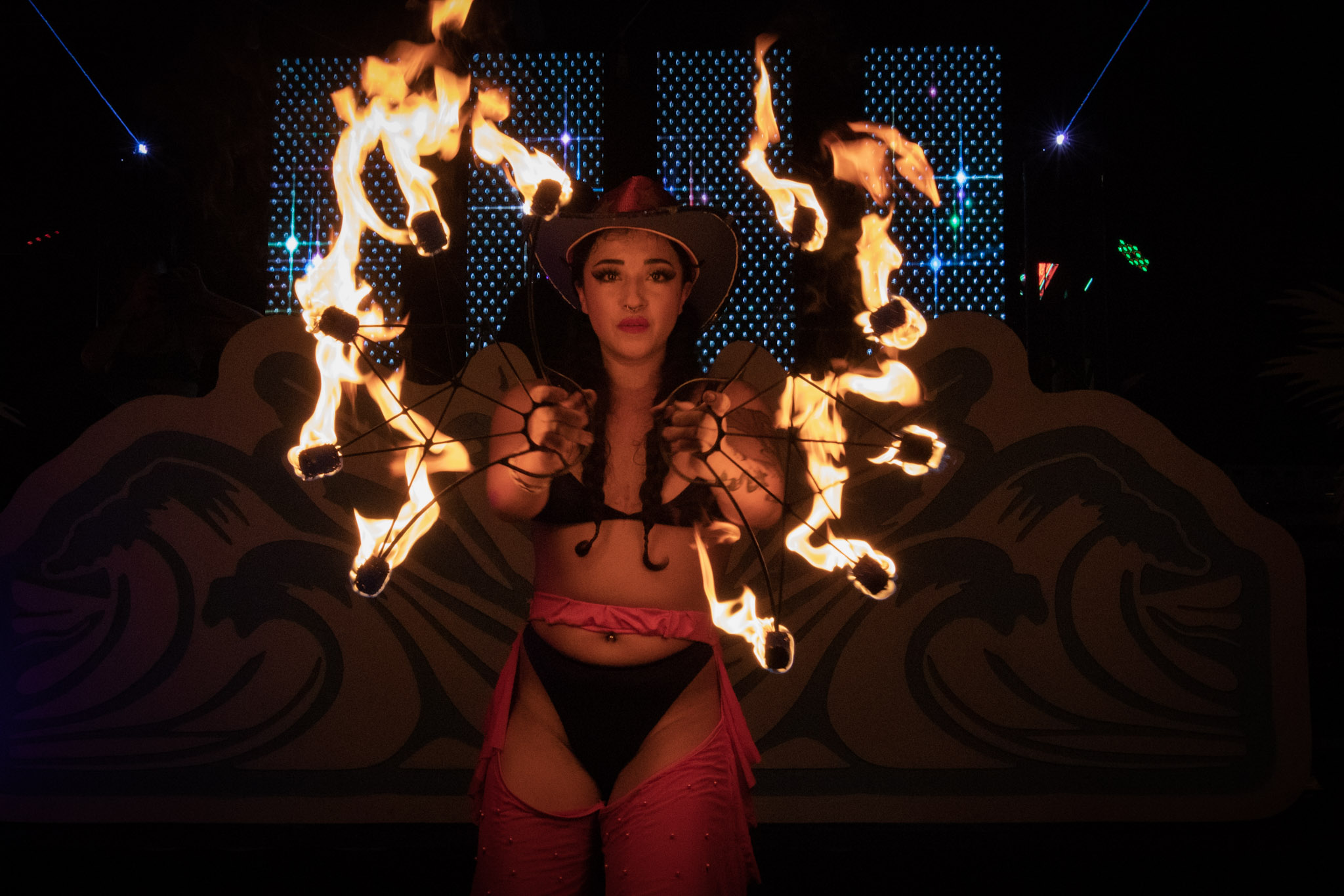 fire performer holds two fire fans